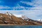 Snowy cliffs rise behind a small settlement on the bay of Adventfjorden Spitsbergen Island-Norway Art Print